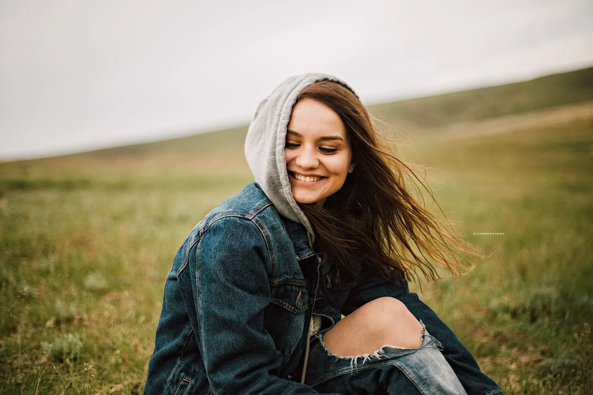 Frau lächelt in Jeansjacke und Kapuze