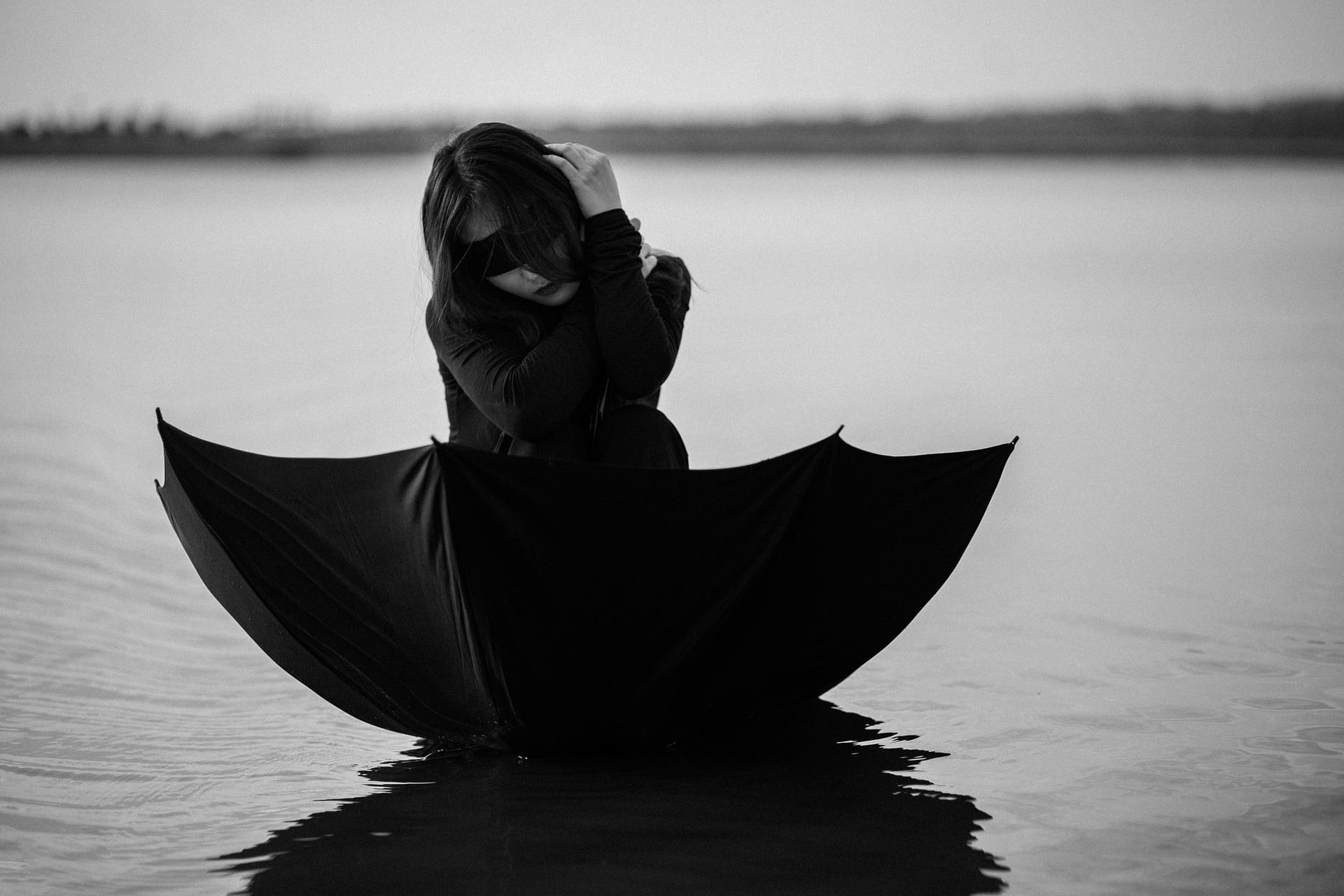 Frau in einem Regenschirm auf dem Wasser.