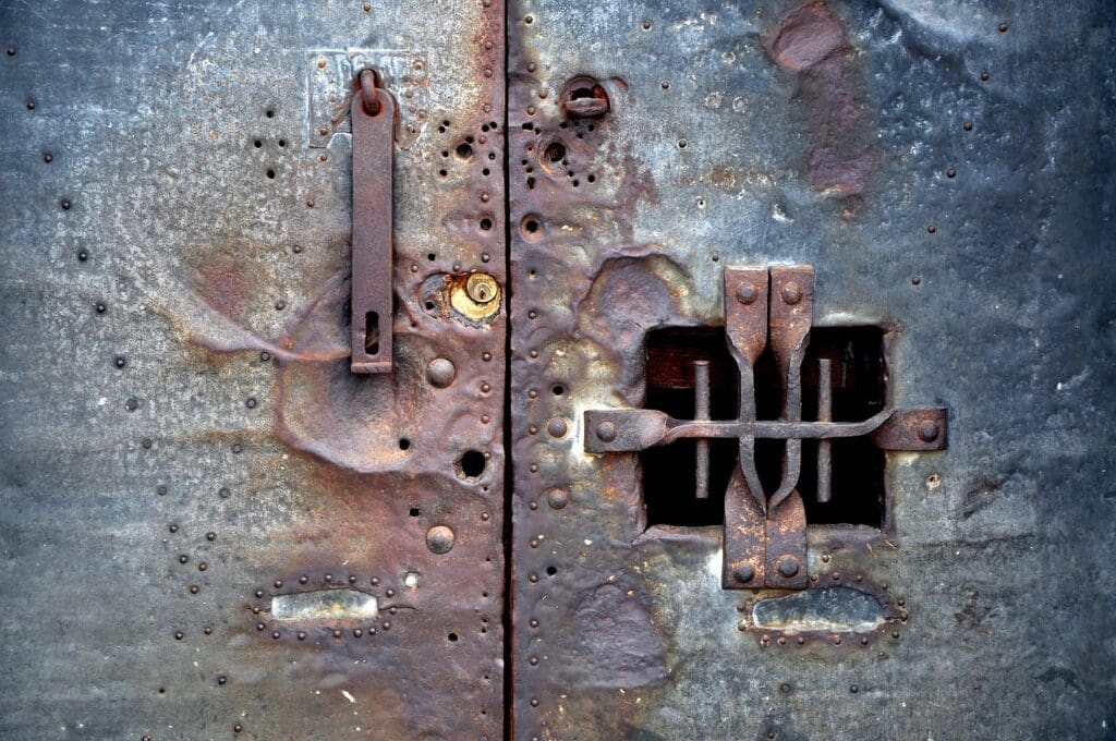 Rostige, alte Metalltür mit Guckloch.